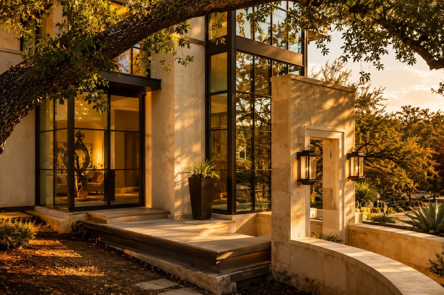 A newly built Austin home of stone, steel, and glass framed by a live oak at golden hour
